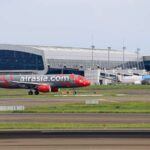 AirAsia plane preparing for takeoff at a bustling airport terminal. Perfect for travel-themed projects.