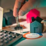 A close-up of real estate financial planning with keys, calculator, and money.